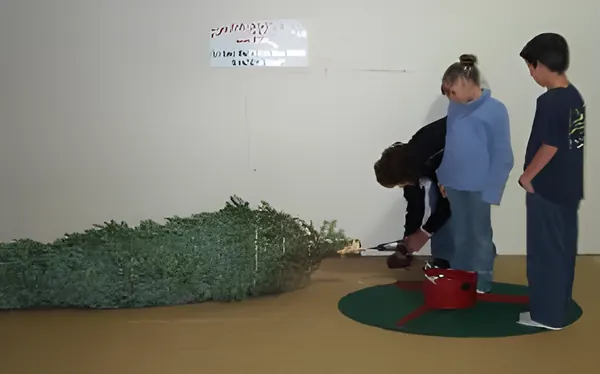 Children setting up a tree in the stand, step 3